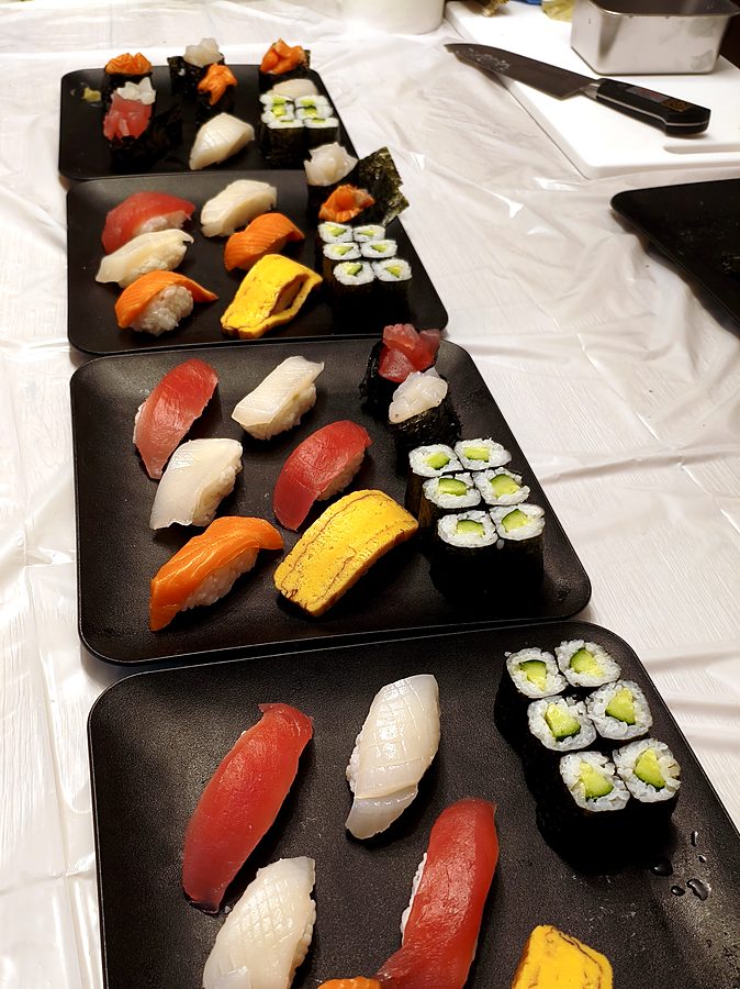 Several plates of sushi made by students lined up on a table
