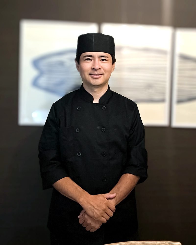 Our sushi instructor in a black chef's uniform and cap