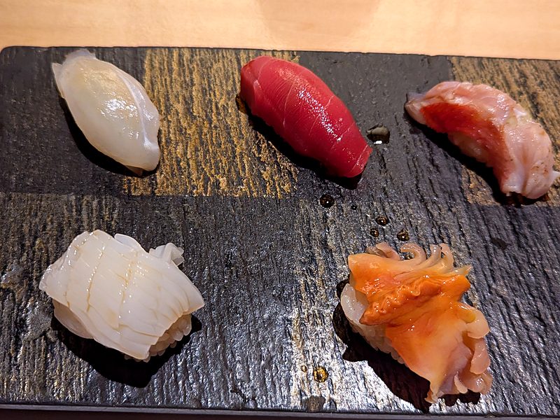 Assorted nigiri sushi on a slate plate